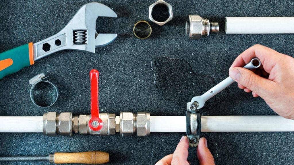 Plumber repairing a pipe valve with an adjustable wrench in Clermont
