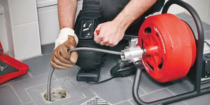 Plumber using a drain-cleaning machine in Clermont