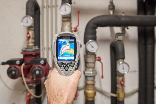 Plumber using a thermal imaging camera to inspect pipes in Clermont