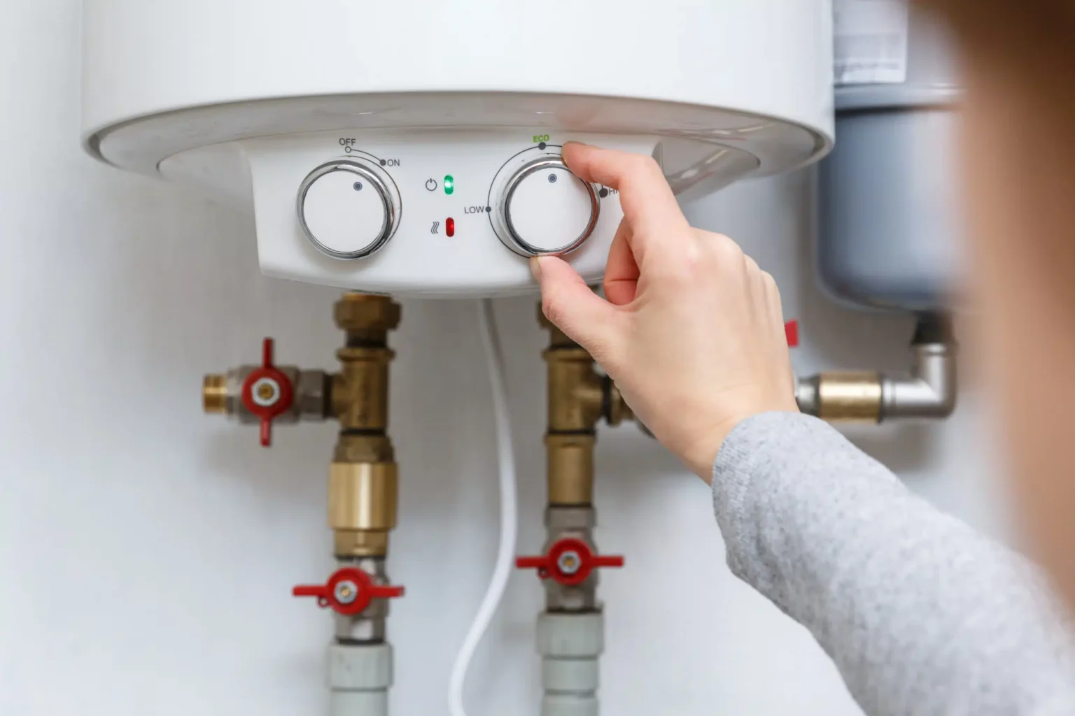 Homeowner adjusting the temperature controls on a water heater in Clermont